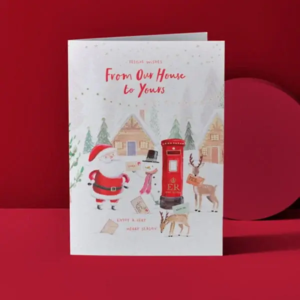 Christmas card featuring Santa, a snowman, reindeer, and a red post box in a snowy village scene.